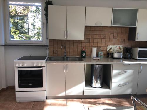 eine Küche mit weißen Schränken und einem Waschbecken in der Unterkunft Lägenhet Thujan, Solrosen i Simrishamn-Österlen in Simrishamn