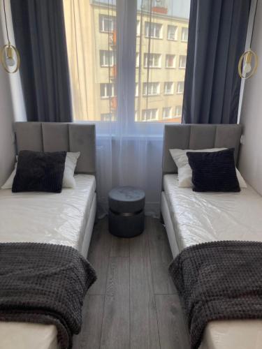 two beds in a small room with a window at Apartament 80’s in Kołobrzeg