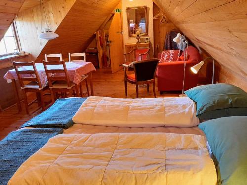 two beds in a room with a table and chairs at Brösarp Källagården Vindsvåning 2 rum och kök in Brösarp