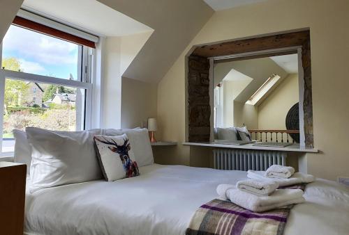 a bedroom with a white bed with towels on it at Oakbank Servant's Quarters in Pitlochry