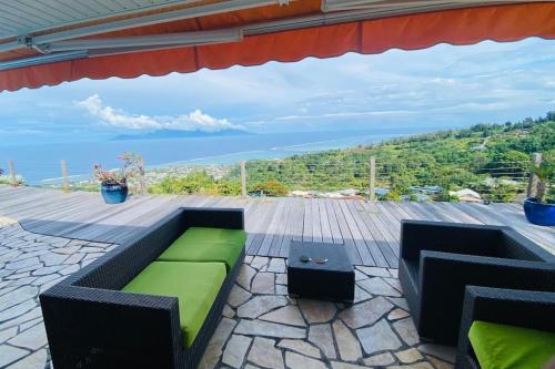 eine Terrasse mit einem grünen Sofa und einem Tisch in der Unterkunft VILLA BOUNTY AMAZING OCEAN VIEW in Punaauia