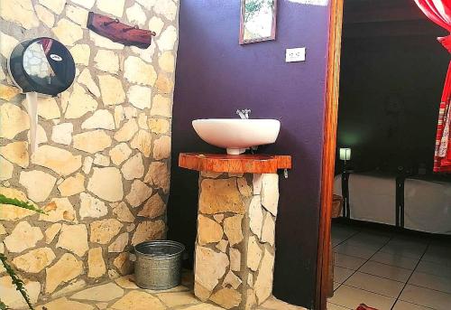 a bathroom with a sink on a stone wall at Alice Guesthouse in El Remate