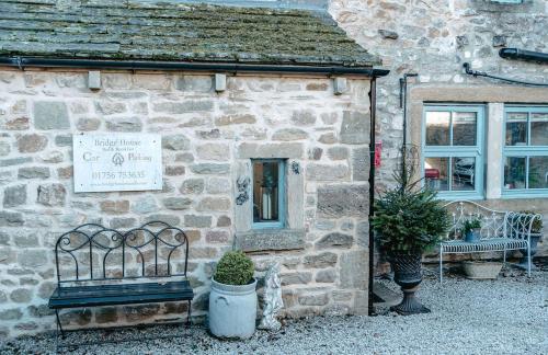a stone building with a bench in front of it at Bridge House B & B Grassington in Grassington