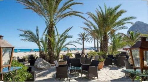 a beach with chairs and palm trees and the ocean at Casa Vacanza Blue Sea in San Vito lo Capo