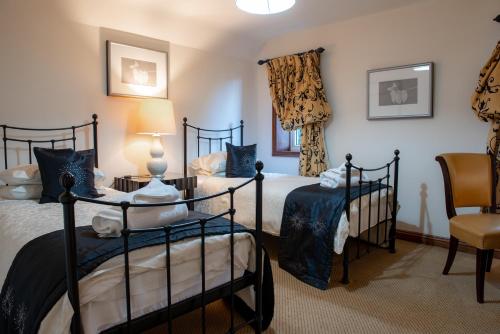 a bedroom with two beds and a chair at Chocbox Cottage - 2 bedroom chocbox cottage with hottub and log fire in Pocklington