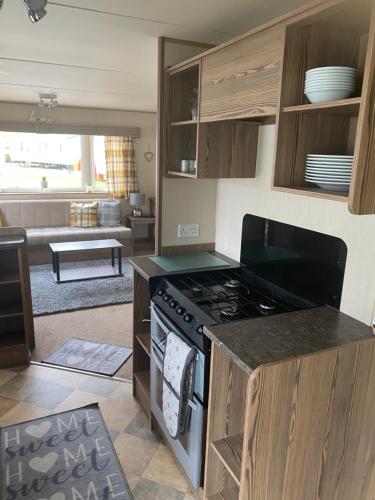 a kitchen with a stove and a living room at Haggerston Castle 6 Berth Caravan - Lakeside North 23 in Cheswick