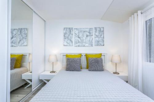 a white bedroom with a large bed with yellow pillows at Vilar do Jardim - Terrace and Pool - Vilamoura in Quarteira