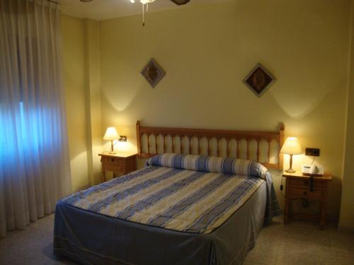 a bedroom with a bed and two night stands with lamps at Hostal El Vegano in Utiel
