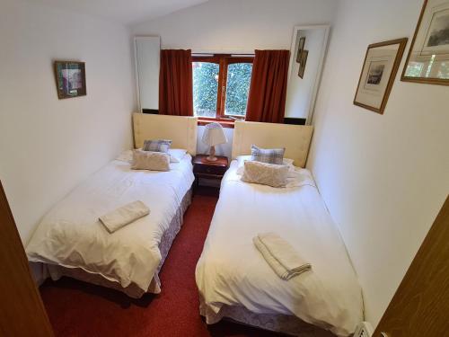 2 camas individuales en una habitación con ventana en Hawthorn Self Catering Cottages, en Benderloch