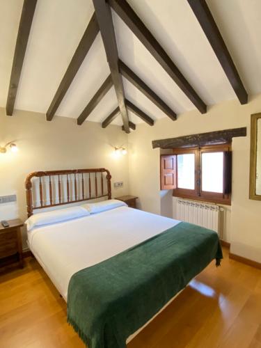 1 dormitorio con 1 cama blanca grande con manta verde en La Casina de la Arquera, en Llanes