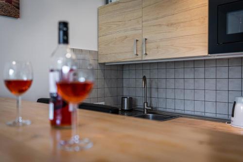 Una botella de vino y dos vasos en una barra de cocina en Apartament Ustronny, en Ustroń