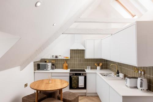 a kitchen with white cabinets and a wooden table at Luxe Design - Boutique Apartment - Heart of Rothbury in Rothbury