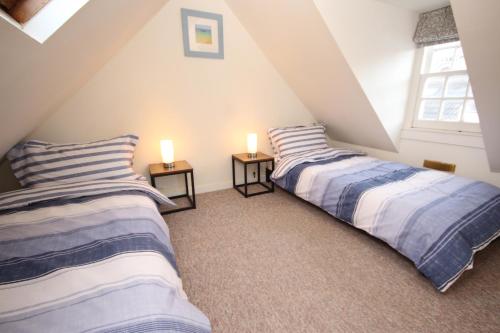 two beds in a attic room with two lamps at Zen Cottage Seatown Cullen in Cullen