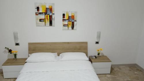 um quarto com uma grande cama branca e duas mesas em CHIARANTO em Menfi