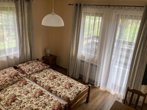 um quarto com uma cama e 2 janelas grandes em Pokoje Gościnne Waluś em Murzasichle