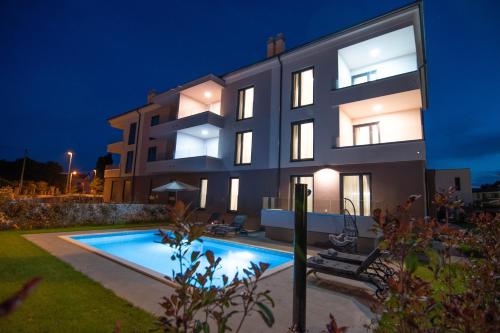 a villa with a swimming pool at night at Luxury apartment Porto with sea view and swimming pool in Premantura