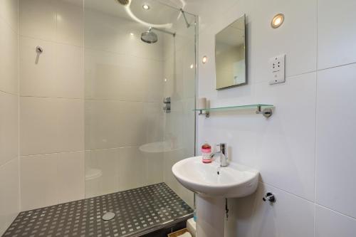 a white bathroom with a sink and a shower at Brown Hill Cottage in Feetham