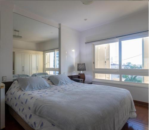 1 dormitorio con 1 cama grande y 2 ventanas grandes en Maison Neoclássica 5 estrelas confort, en Ribeirão Preto