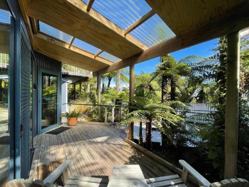 eine offene Veranda mit einer Holzterrasse mit Bäumen und Aussicht in der Unterkunft Hydrangea Cottages in Punakaiki