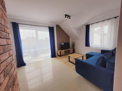a living room with a blue couch and large windows at Apartamenty Morski Brzeg - Sauna, Balia in Władysławowo