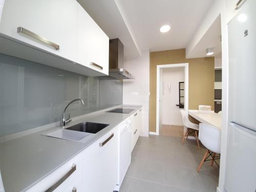 a kitchen with white cabinets and a sink and a table at Brisa Marina in A Guarda