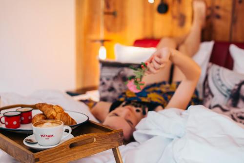 a person laying in bed with a tray of food at PEST-BUDA Design Hotel by Zsidai Hotels at Buda Castle in Budapest