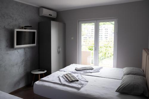 a bedroom with a bed with a tv on the wall at Guest House Mrvaljević in Budva