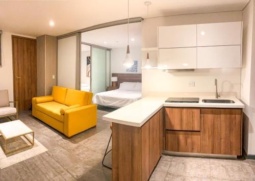 a kitchen with a yellow chair and a room with a bed at Gz Tower Apartamento Barranquilla in Barranquilla