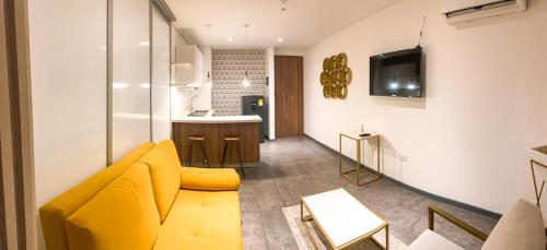 a living room with a yellow couch and a kitchen at Gz Tower Apartamento Barranquilla in Barranquilla
