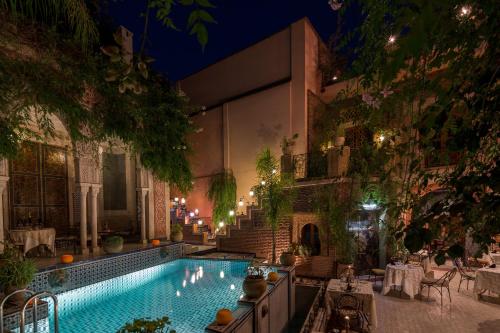 a swimming pool in a courtyard at night at Riad Palais Sebban in Marrakech