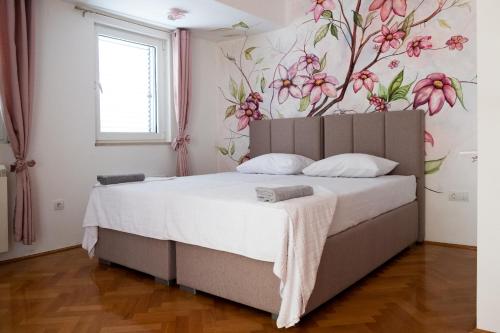 - une chambre avec un lit orné d'une fresque murale représentant des fleurs dans l'établissement Guest House Mrvaljević, à Budva
