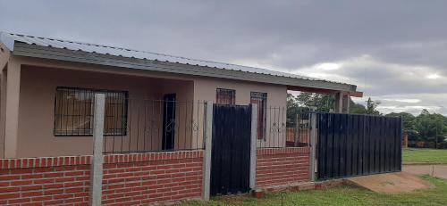 a house with a fence and a gate at Casa con piscina en Gobernador Roca in Gobernador Roca