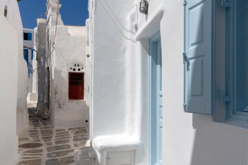 a narrow alley with white buildings and blue doors at Skepi Town Houses in Mýkonos City
