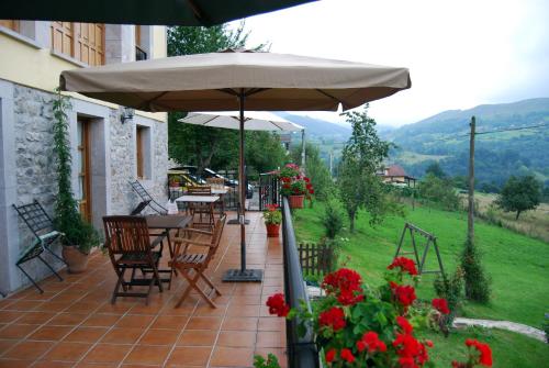 un patio con sombrilla, sillas y flores en Balcón Picos de Europa, en Narciandi