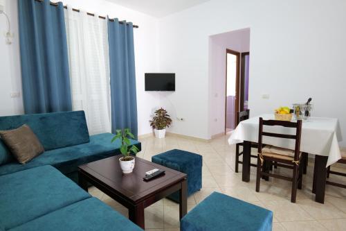 sala de estar con sofá azul y mesa en Ernest Apartments, en Sarandë