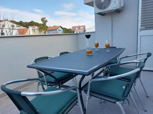uma mesa e cadeiras numa varanda com bebidas em Apartman Stella Marina em Sibenik