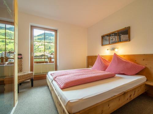 um quarto com uma cama com almofadas vermelhas e uma janela em Blick zum Mayrhofen em Ramsau im Zillertal