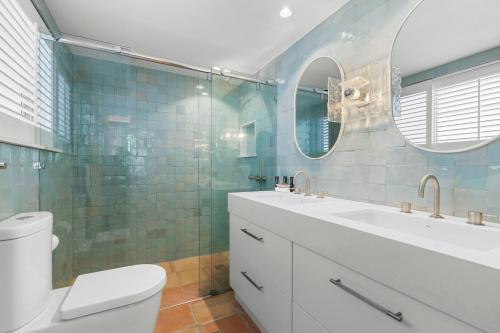 a bathroom with a sink and a toilet and a mirror at La Mer Apartments in Noosa Heads