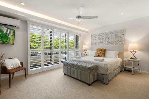 a white bedroom with a bed and a window at La Mer Apartments in Noosa Heads