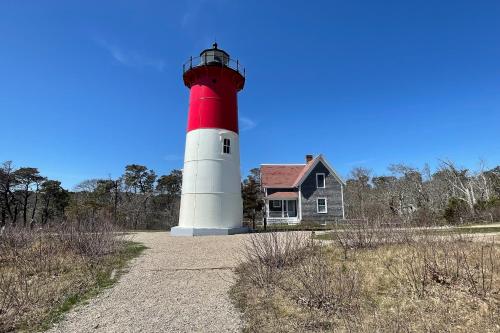 a red and white lighthouse sitting next to a house at Endless Dunes, A Modern Motel in Eastham