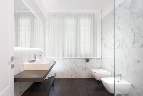 a white bathroom with two sinks and a toilet at TURINHOMETOWN Residence Apartments in Turin