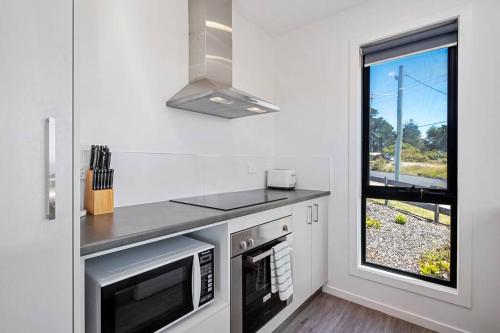 a kitchen with a stove and a sink and a window at Bordaga Unit 1 in Scamander
