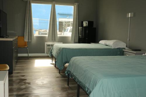 Una habitación de hotel con dos camas y una ventana. en Travel Inn Fort Pierce, en Fort Pierce