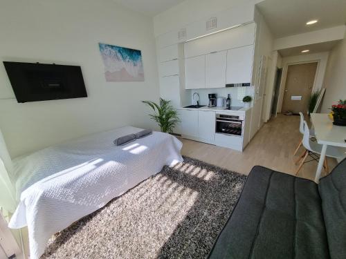 a white bedroom with a bed and a kitchen at Penthouse in the Oulu center in Oulu