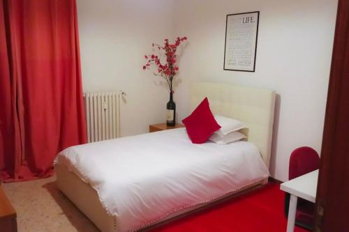 um quarto com uma cama branca e uma almofada vermelha em Unique & beautiful bedroom in central of Florence em Florença