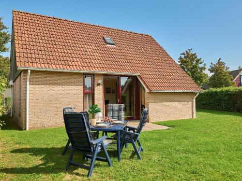 a table and chairs in front of a house at Holiday Home in Zeeland with Sauna in Heinkensand