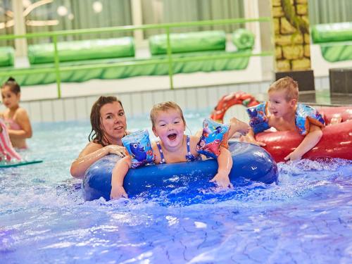 a woman and three children in a swimming pool at Holiday Home in Zeeland with Sauna in Heinkensand