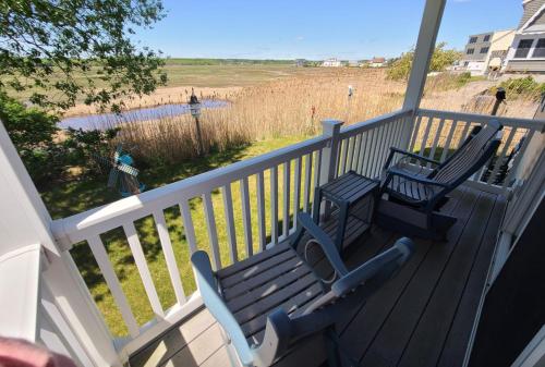 two benches sitting on a deck with a view of the beach at Moody's Motel and Cottages in Wells