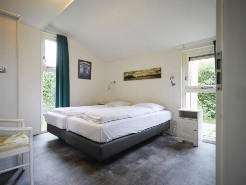 um quarto com uma cama grande e uma janela em Cozy holiday home with wellness located in Zeeland em heinkenszand