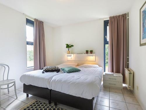 1 dormitorio con 1 cama grande en una habitación con ventanas en Cozy holiday home with two bathrooms, in Zeeland, en Heinkensand